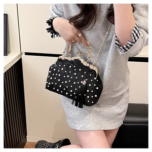 Detail of elegant black satin evening bag with white pearl beads and gold chain strap