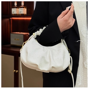 Detail of white crocodile embossed texture leather handbag with pleated handle and gold hardware
