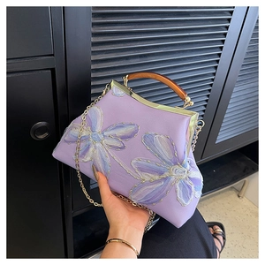Detail of lavender embroidery handbag with metal clasp and brown bamboo style handle