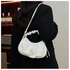 Detail shot of the white fish-scale textured ruched bag worn by a model in a black blazer
