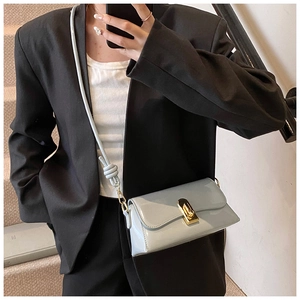 Model wearing a light blue glossy small square crossbody bag with gold buckle hardware