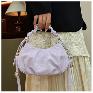 Close-up of lilac fish-scale embossed handbag featuring pleated handle and gold ball detail
