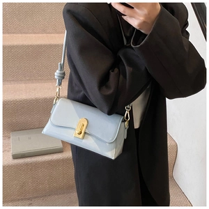 Detail of light blue square shoulder bag with gold clasp and knotted strap detail