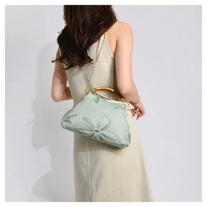 Detail of light mint green frame bag with floral embroidery and wooden handle