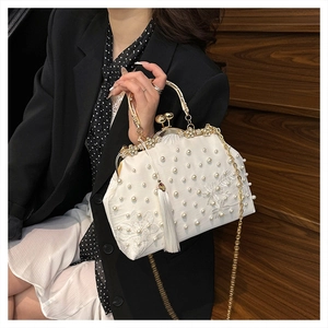 Detail view of pearl embroidery handbag with golden chain and floral accents