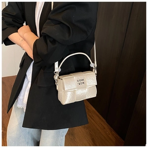 Detail of cream woven square bag with metallic finish and adjustable shoulder strap