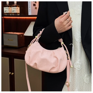 Close-up of pink pleated crescent bag with snakeskin texture and golden hardware