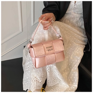 Detail of pink woven leather square bag with decorative beads and metallic logo