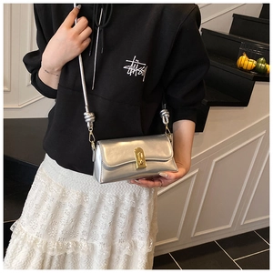 Detail of silver rectangular crossbody bag with golden lock and sphere knot strap