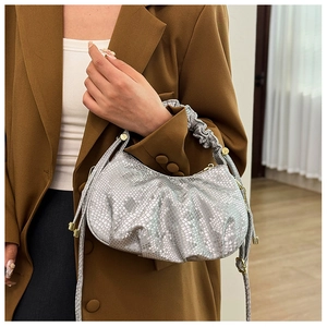 Detail view of silver pleated handbag with snakeskin texture and ruffled top handle