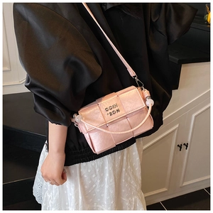 Detail view of pink woven square bag with beaded handle and metal logo for women