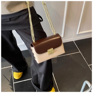 Detail of a chic two-tone crossbody bag with brown leather flap and gold chain strap
