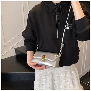Detail of silver metallic crossbody bag with golden twist lock and knotted strap design