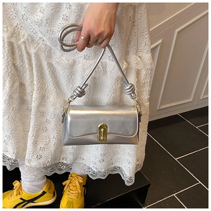 Detail of silver metallic crossbody bag with golden twist lock and textured strap