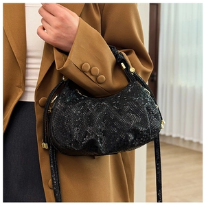 Close-up of black scale textured pleated handbag with gold hardware and leather details