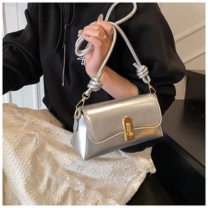 Detail of silver metallic crossbody bag featuring golden twist lock and knot shoulder strap