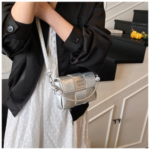 Close-up of metallic silver woven crossbody bag featuring metal buckle and slim strap