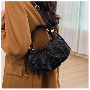 Detail of black snake pattern mini bag with pleated handle and gold hardware detail