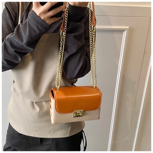 Detail of a chic orange and beige crossbody bag with gold chain strap and metal turn lock