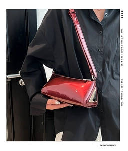 Detail of burgundy patent leather triangle baguette bag with silver metal side accents