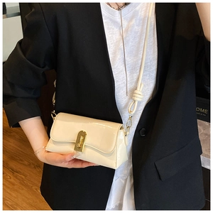 Detail of cream crossbody bag with gold buckle and unique knot shoulder strap detail