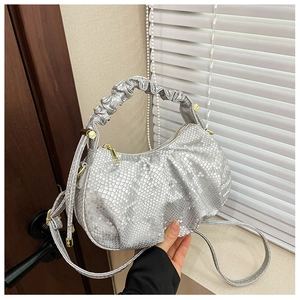 Detail of silver fish-scale textured pleated handbag with golden metallic hardware