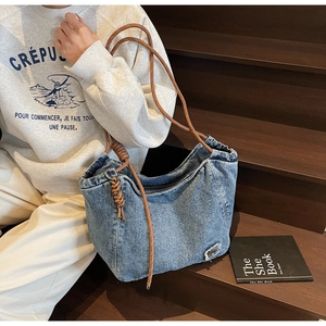 Detailed macro view of denim tote bag featuring decorative rope knots and distressed patches