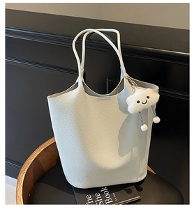 Close-up of lychee grain leather bucket bag in light grey with a plush cloud charm