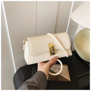 Detail of a beige glossy square handbag with a gold twist lock and a round metal handle