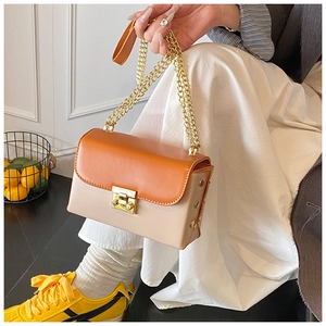 Detail view of a color-block flap bag with gold chain strap and turn-lock closure