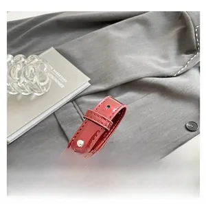 Detail of adjustable strap with silver studs on wine red patent leather baguette bag