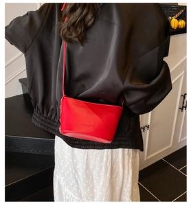 Modella che indossa una borsa a secchiello rossa in pelle martellata in uno studio