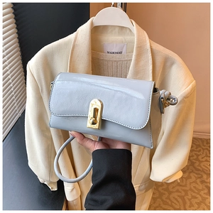 Detail of light blue patent leather shoulder bag with glossy finish and gold metal lock