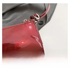Detail of burgundy patent leather underarm bag featuring silver zipper and stitching