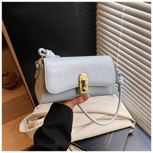 Detail of light blue glossy square bag with gold metal buckle and knotted leather strap