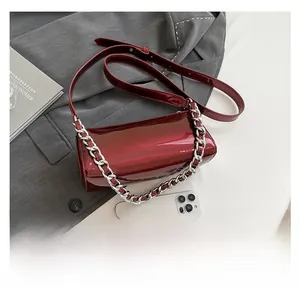 Close-up of wine red patent leather baguette bag with silver chain and shoulder strap