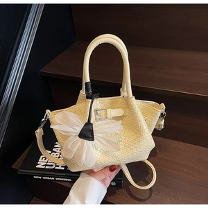 Vue détaillée du sac cabas jaune à texture tressée avec pendentif fleur en voile