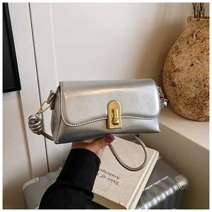 Detail of silver metallic handbag with gold oval clasp and round decorative metal ball