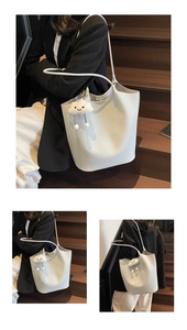 Detail view of lychee pattern leather tote bag with cloud plush charm in a commuter style