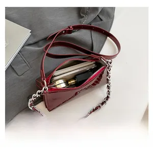 Interior capacity detail of a dark red patent leather baguette bag with silver chain