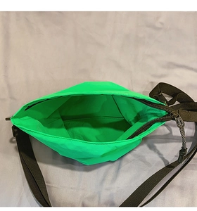 Vue de dessus d'un sac bandoulière en nylon vert fluo montrant l'intérieur et le zip noir