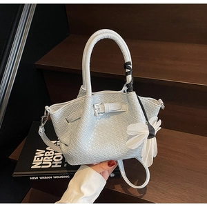 Détail du sac à main en cuir tressé bleu clair avec boucle argentée et breloque fleur