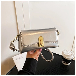 Close-up of a silver mirror finish crossbody bag with a golden metallic twist lock