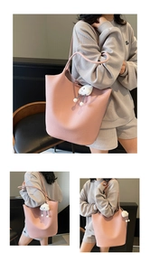 Close-up of pink lychee pattern leather tote bag with white cloud plush pendant accessory