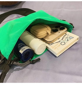 Vue intérieure du sac bandoulière vert fluo montrant l'espace pour téléphone et soins