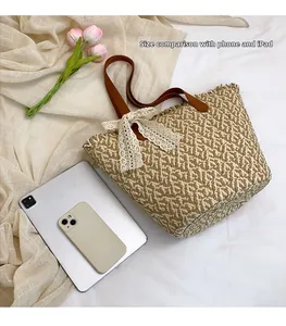 Detail view of woven straw tote bag showing size comparison with phone and tablet