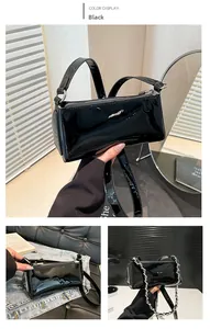 Detail of black patent leather baguette bag with silver chain and glossy finish