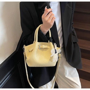 Détail d'un sac à main jaune tissé avec charm floral et bandoulière sur un escalier en bois