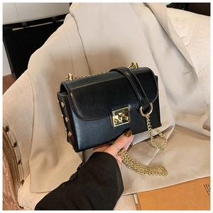 Close-up of black crossbody bag with gold turn-lock, rivets, and chain strap detail