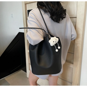 Detail view of black lychee grain bucket bag with cute white cloud plush pendant accessory